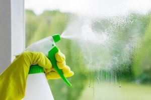 terceirização de serviço - pessoa apertando um spray para limpar uma janela